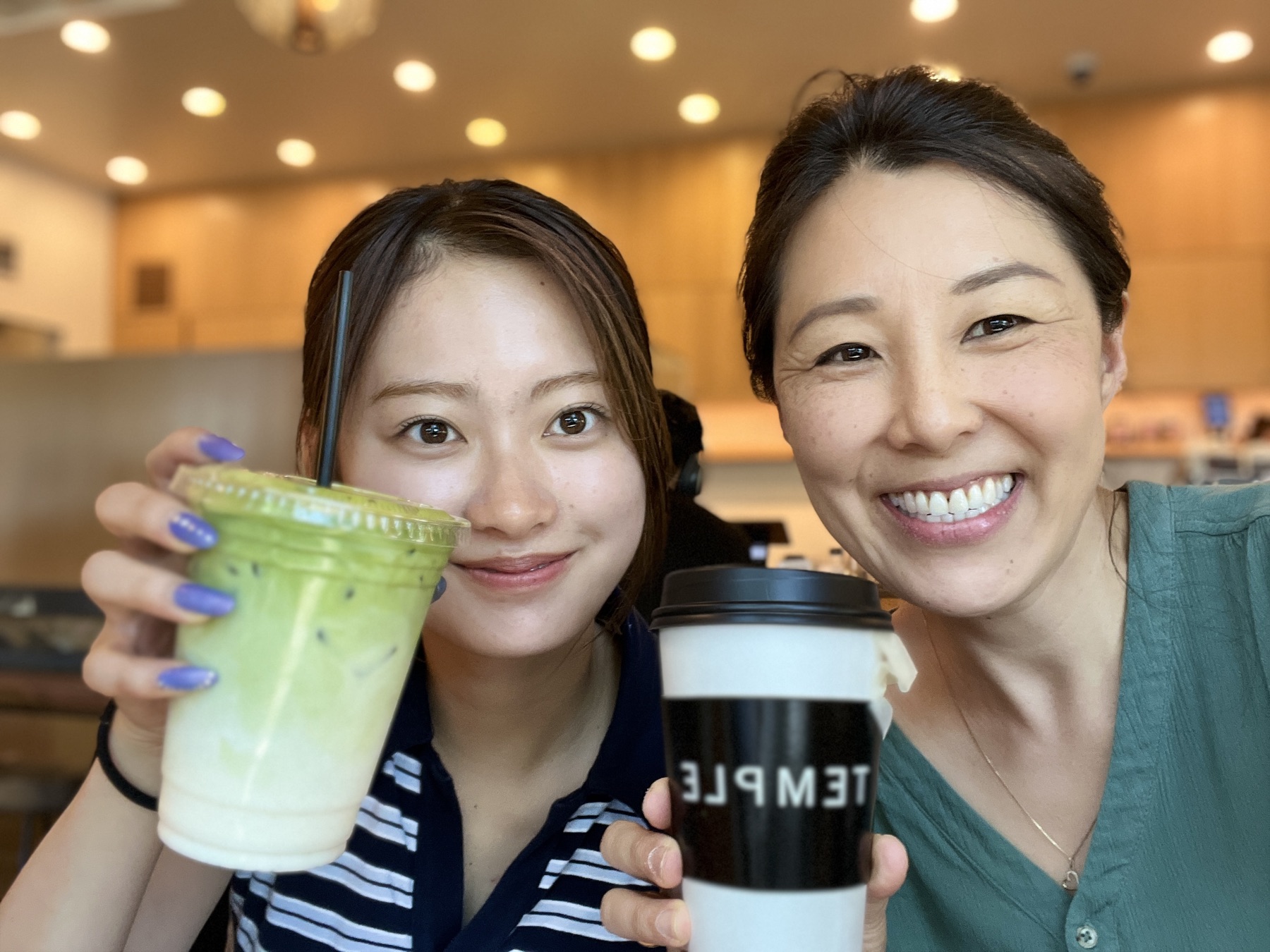 A mentor and a student holding their drinks at a cafe